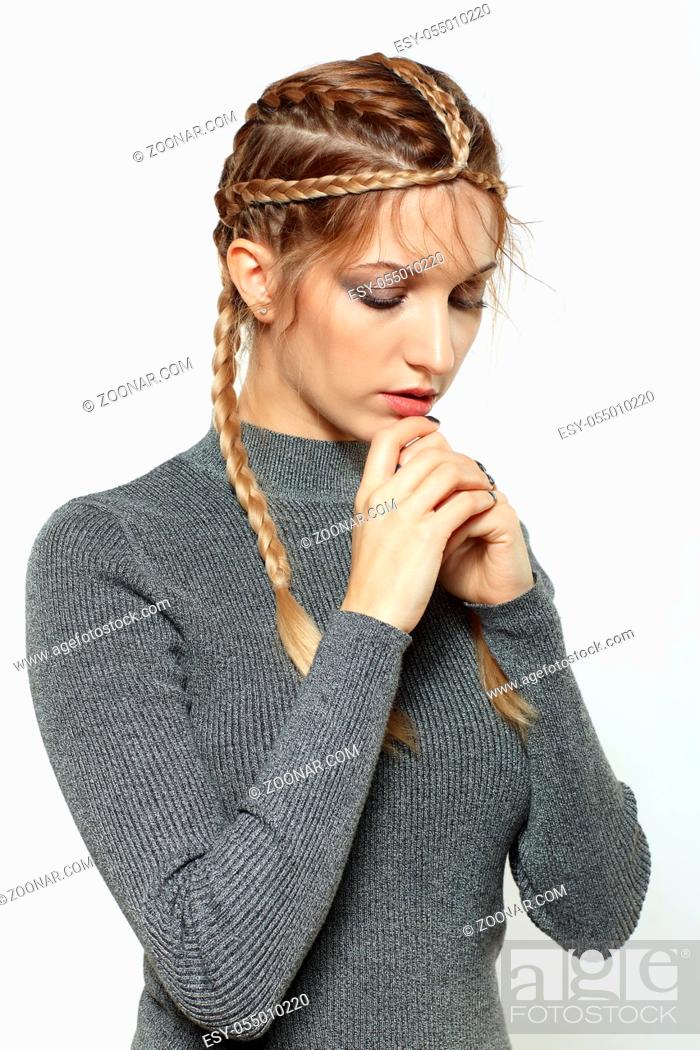 Stock Photo: Portrait of beautiful young dark blonde woman. Female with creative braid hairdo on gray background. Girl with hands near face.