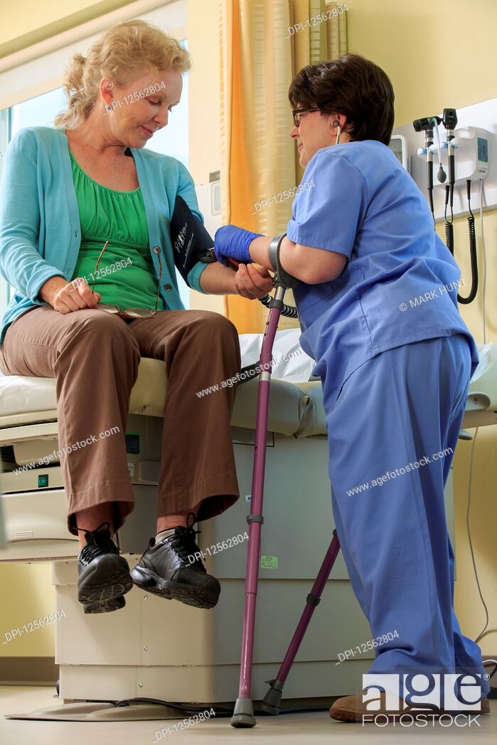 Stock Photo: Nurse with Cerebral Palsy taking a patient's blood pressure in a clinic.