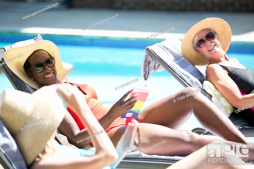 Stock Photo: Happy senior women friends sunbathing at sunny summer poolside.