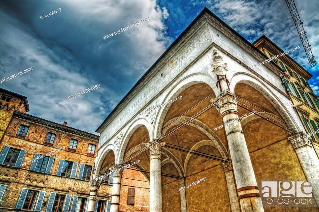 Stock Photo: Loggia del Papa under a grey sky with clouds in Siena, Italy.