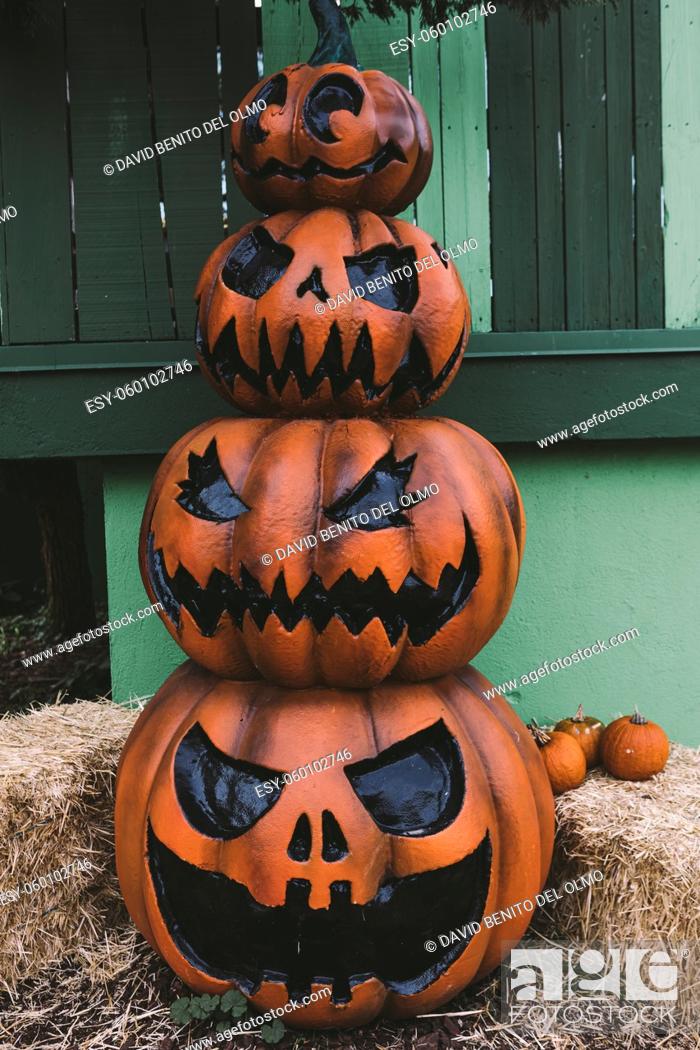 Stock Photo: Three decorative Halloween Jack-o-Lantern pumpkins, one on top of the other, on the street. Halloween and carnival celebration concept.