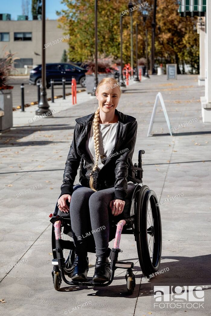 Stock Photo: Young paraplegic woman in her wheelchair on a city walkway on a beautiful fall day; Edmonton, Alberta, Canada.