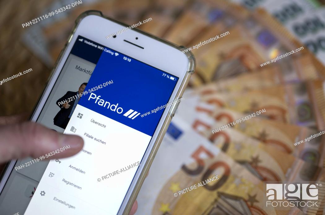 Stock Photo: PRODUCTION - 14 November 2022, Berlin: The screen of a smartphone shows the open app of the Pfando vehicle pawnshop, while banknotes are lying on a table in the.