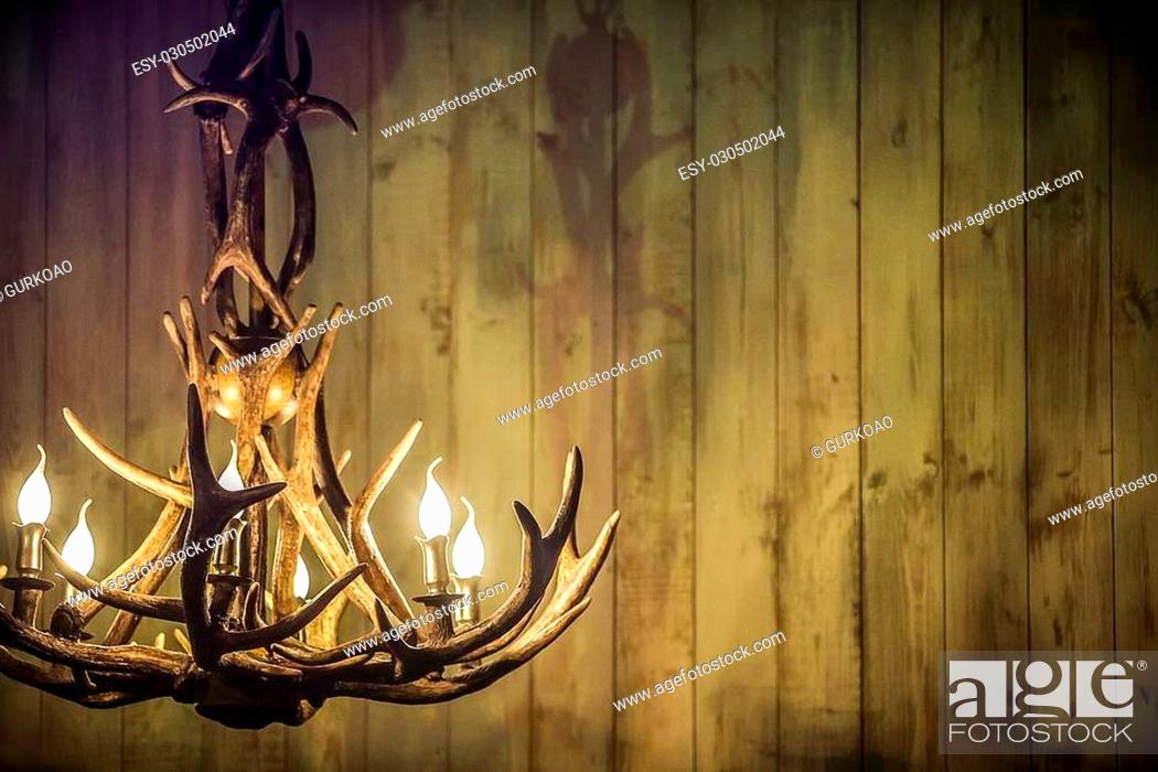 Stock Photo: moose antlers as a lamp on the background of old boards.