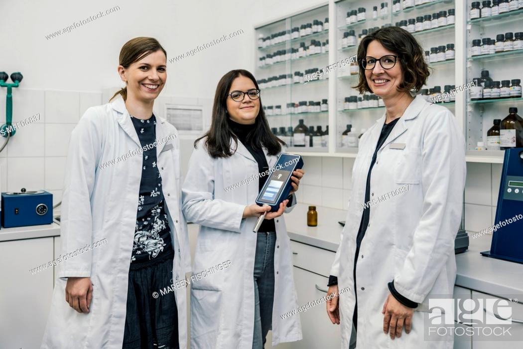 Stock Photo: Smiling female pharmacists with NIR spectrometer in chemist store.