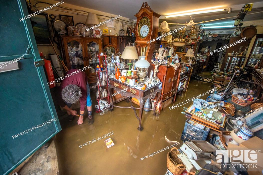 Stock Photo: 13 December 2022, Portugal, Lissabon: The owner of an antique store is in his flooded store. Heavy rains have caused damage to streets.