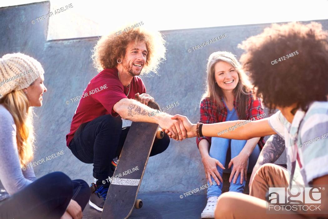 Stock Photo: Friends with skateboards handshaking at sunny skate park.