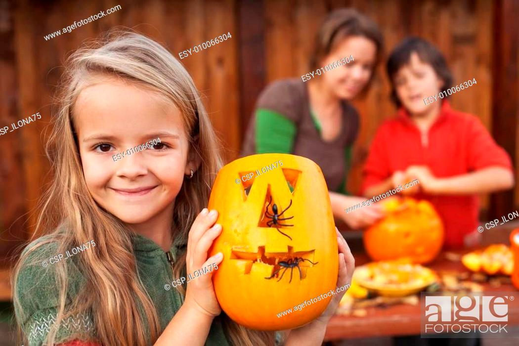 Stock Photo: Little girl showing her Halloween jack-o-lantern.