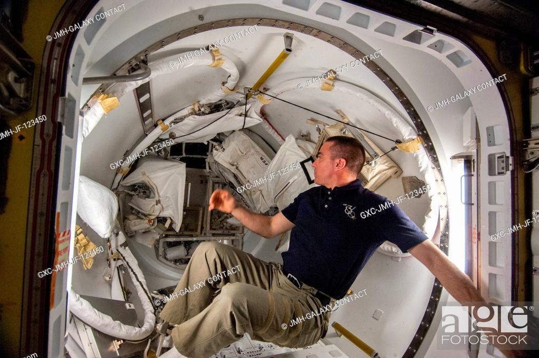 Stock Photo: NASA astronaut Chris Cassidy, Expedition 36 flight engineer, works with spacewalk equipment in the Quest airlock of the International Space Station in.