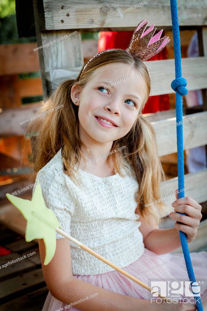 Stock Photo: Girl dressed as a princess with crown and sceptre playing in a tree house.