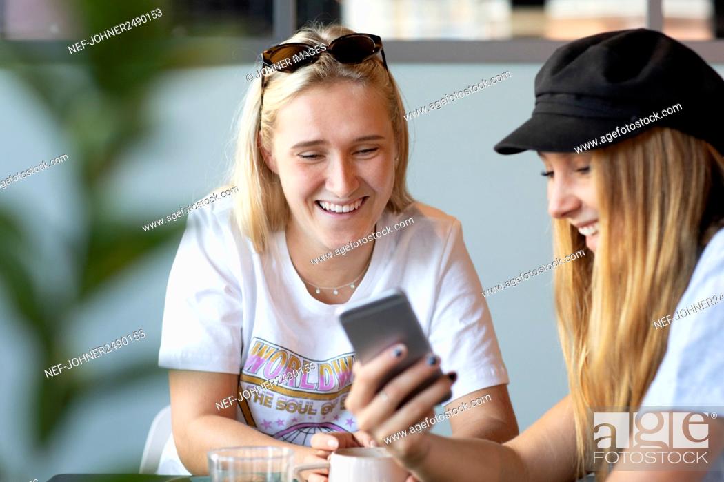 Stock Photo: Female friends looking at cell phone in cafe.