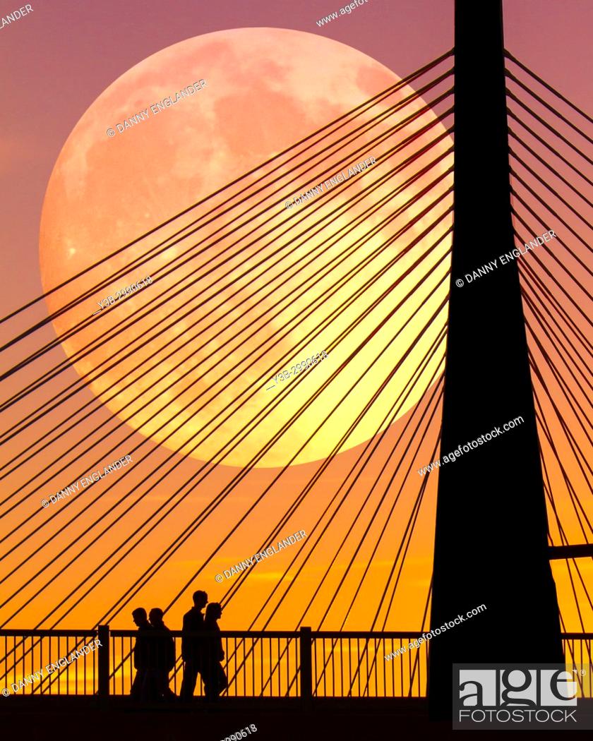 Stock Photo: Silhouettes of people at sunset, walking near the Zakim Bridge in Boston, Massachusetts, as the full moon rises.