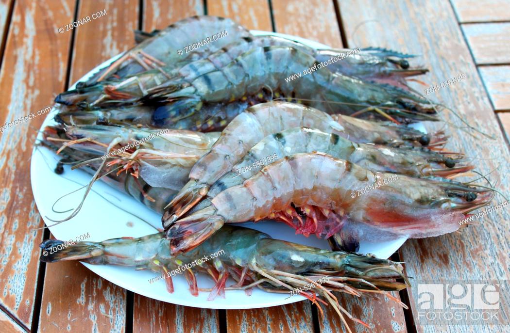 Stock Photo: Fresh Shrimp on plate are located on old garden table.