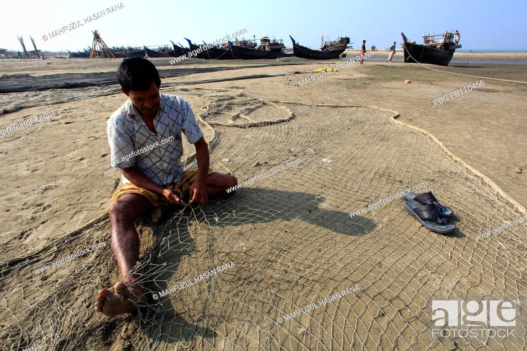 Stock Photo: Fisherman repairs fishing net CoxÆs Bazar, Bangladesh November 2010.