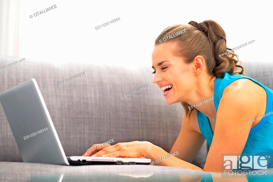 Stock Photo: Young woman using laptop in living room.