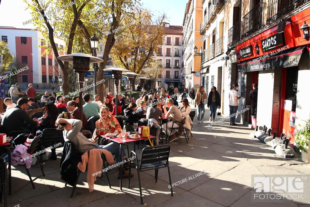 Stock Photo: PRODUCTION - 11 December 2021, Spain, Madrid: Customers sit on the terrace of a bar in the center of Madrid. Although the Corona numbers are also on the rise.