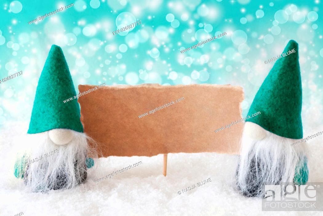 Stock Photo: Christmas Greeting Card With Two Turqoise Gnomes. Sparkling Bokeh Background With Snow. Copy Space For Advertisement.