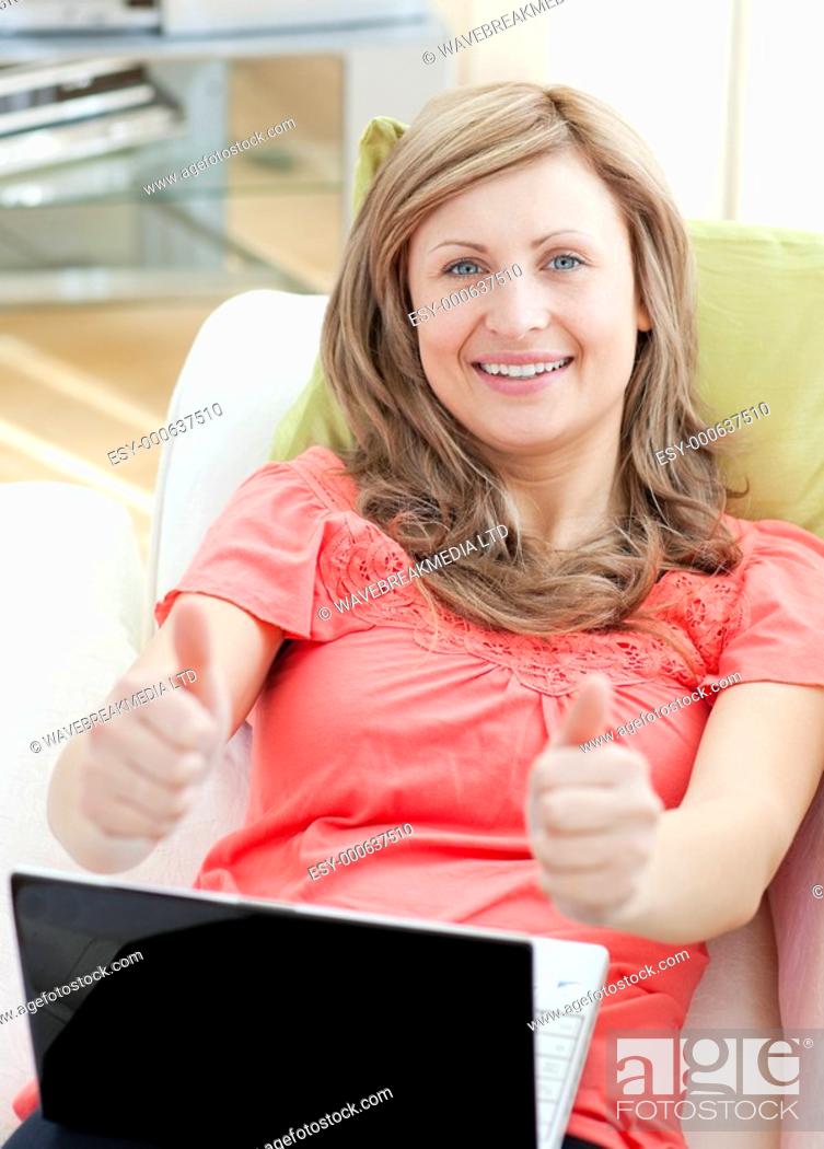 Stock Photo: Successful woman using a laptop sitting on a sofa in the living-room.