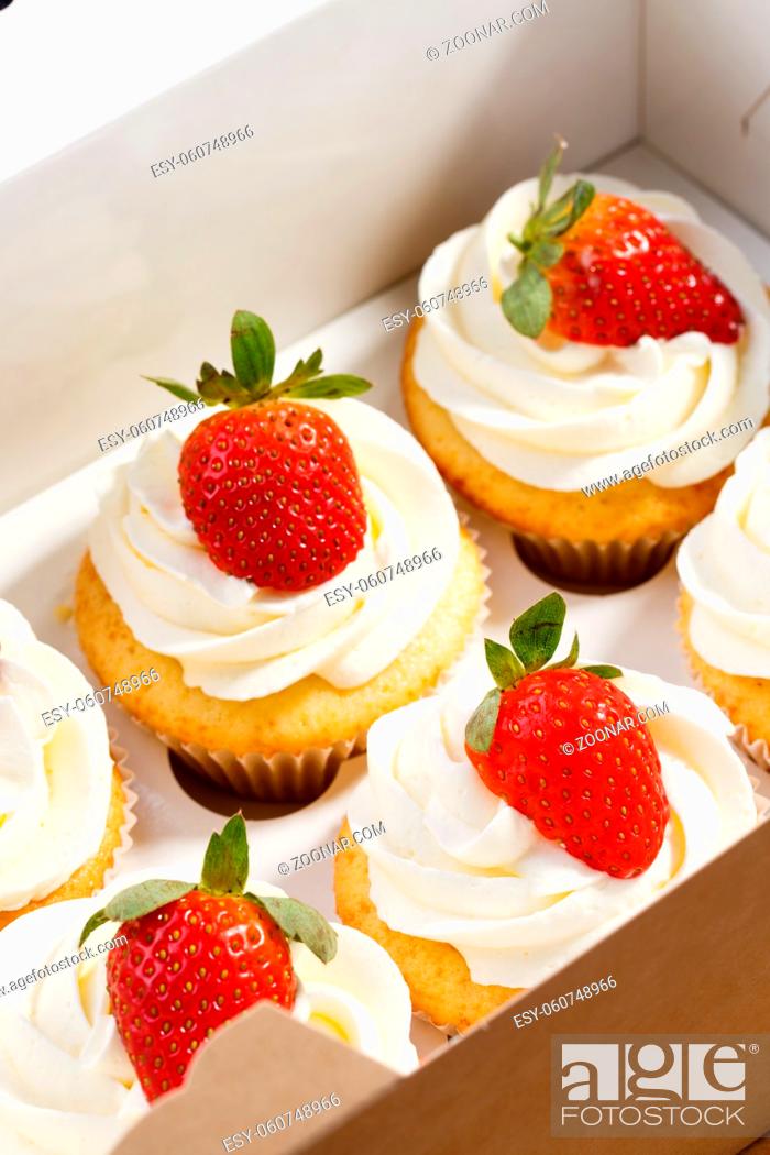 Stock Photo: strawberry capcake in a cardboard box on an olive board.