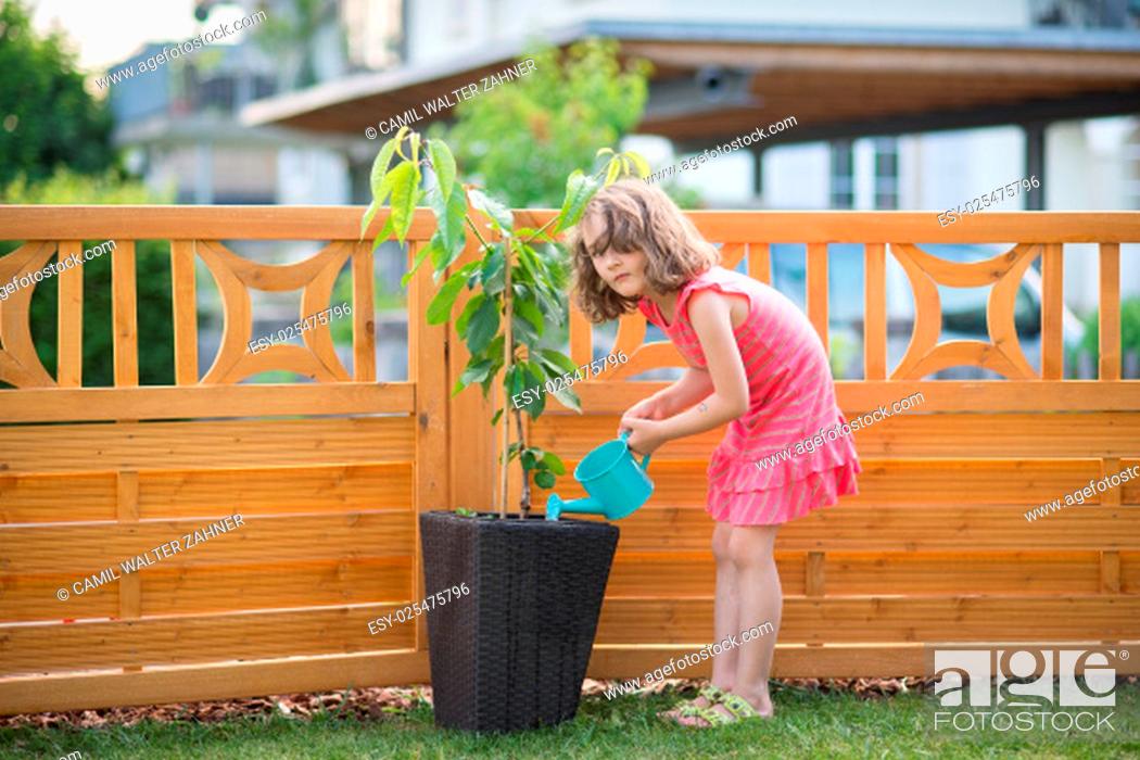 Stock Photo: Happy little girl watering plants in the garden.