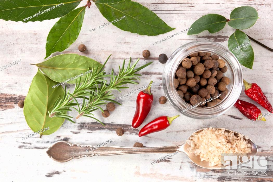 Stock Photo: Bay leaves, traditional spice and condiment on white wooden background. Bay leaves, rosemary, chillies and black pepper on white wooden table, top view.