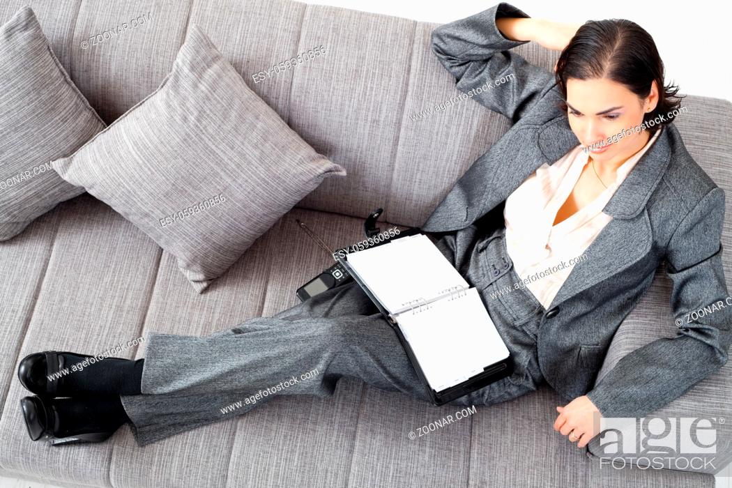 Stock Photo: Young businesswoman sitting on sofa, working, overhead view.