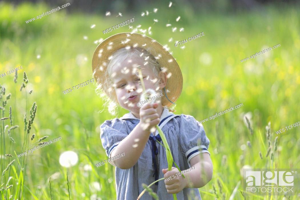 Stock Photo: Germany, Bavaria, Girl blowing dandelion seed in meadow.