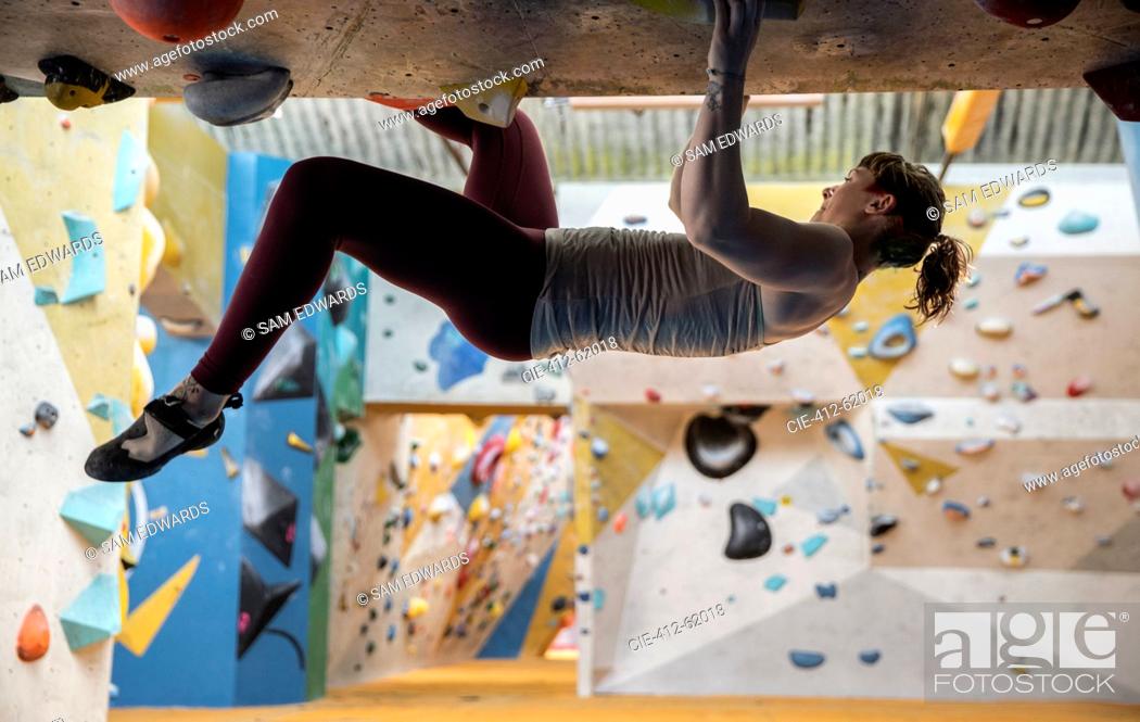 Stock Photo: Young woman rock climbing upside-down.