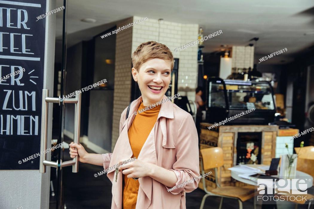 Stock Photo: Female cafe owner unlocking the door in the morning.