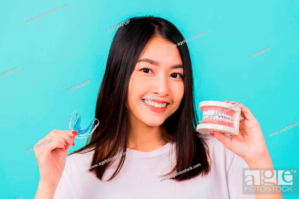 Stock Photo: Portrait young Asian beautiful woman smiling holding silicone orthodontic retainers for teeth retaining tools after removable braces.