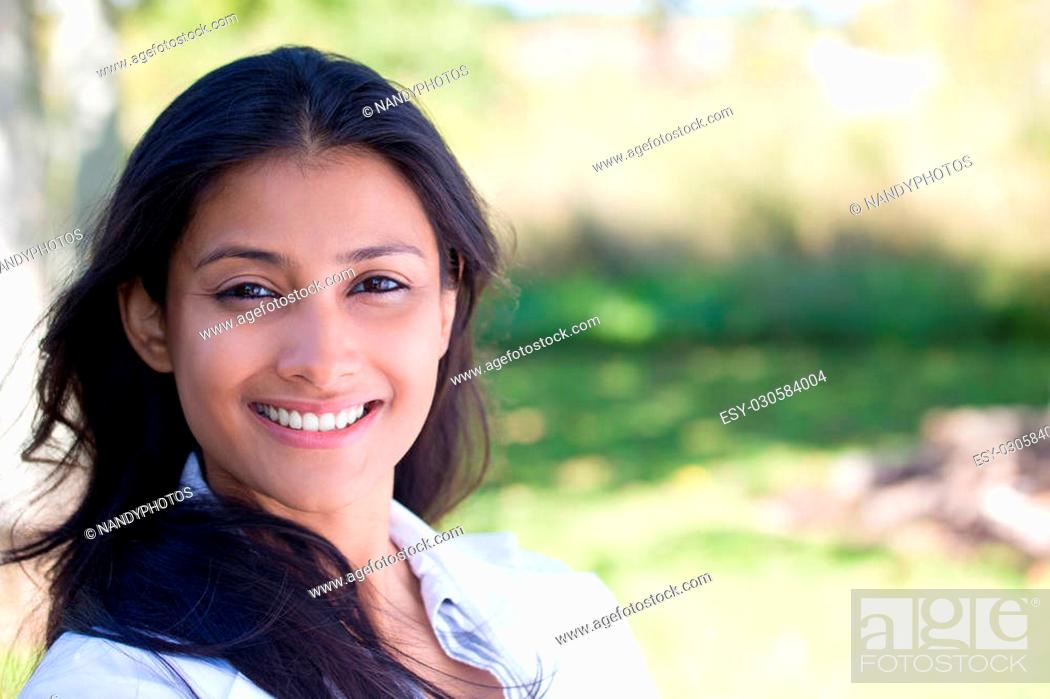 Stock Photo: Closeup portrait of confident smiling happy pretty young woman in gray suit, isolated background of blurred trees. Positive human emotion facial expression.