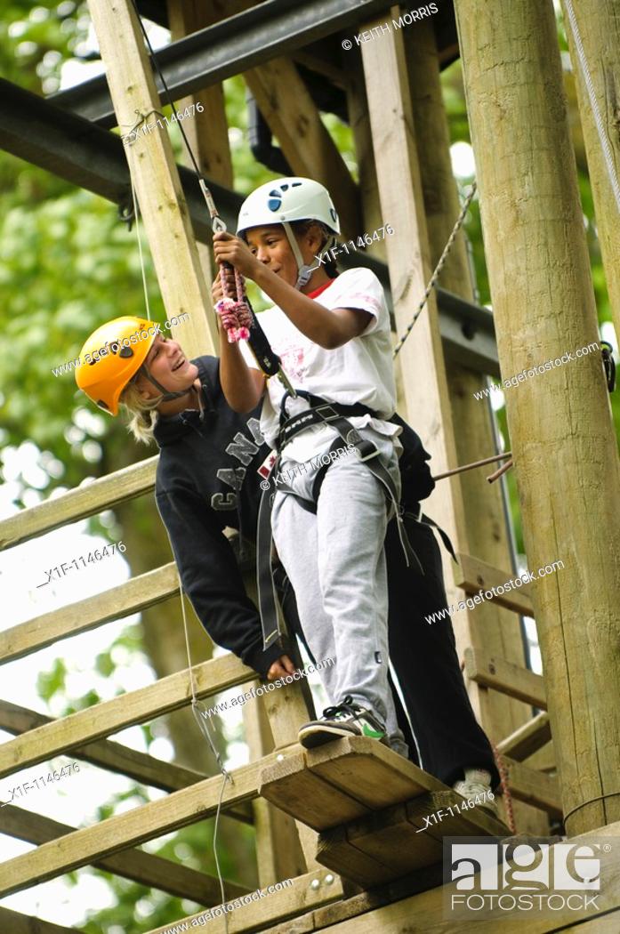 Stock Photo: Teenagers on high ropes in the trees as part of a course organised by the Canolfan Yr Urdd outward bound adventure centre, Glanllyn, Bala, North Wales UK.