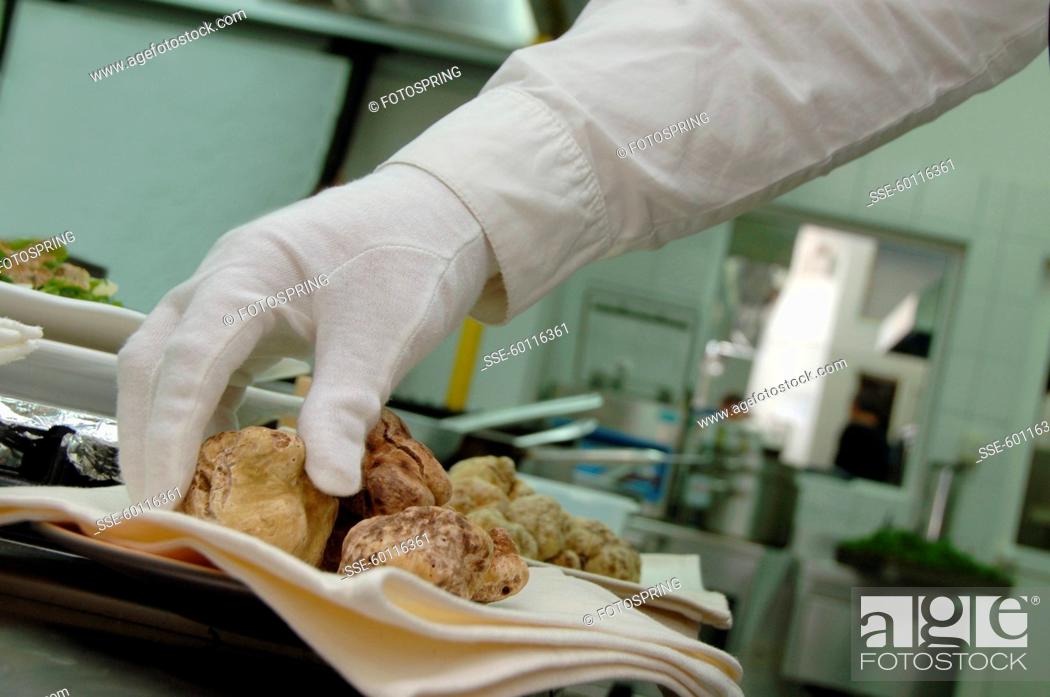 Photo de stock: Man wearing a white glove and taking a white truffle from the plate.