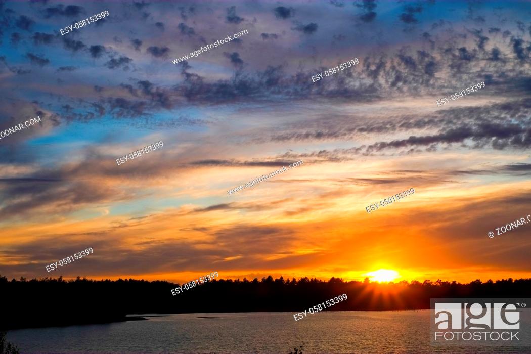 Stock Photo: Dramatic and colorful sunset over a forest lake reflected in the water. Blakheide, Beerse, Belgium. High quality photo.