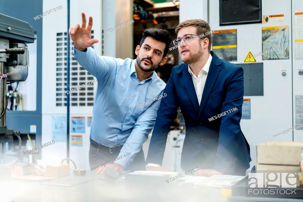 Stock Photo: Manager doing hand gesture while discussing with businessman at manufacturing industry.