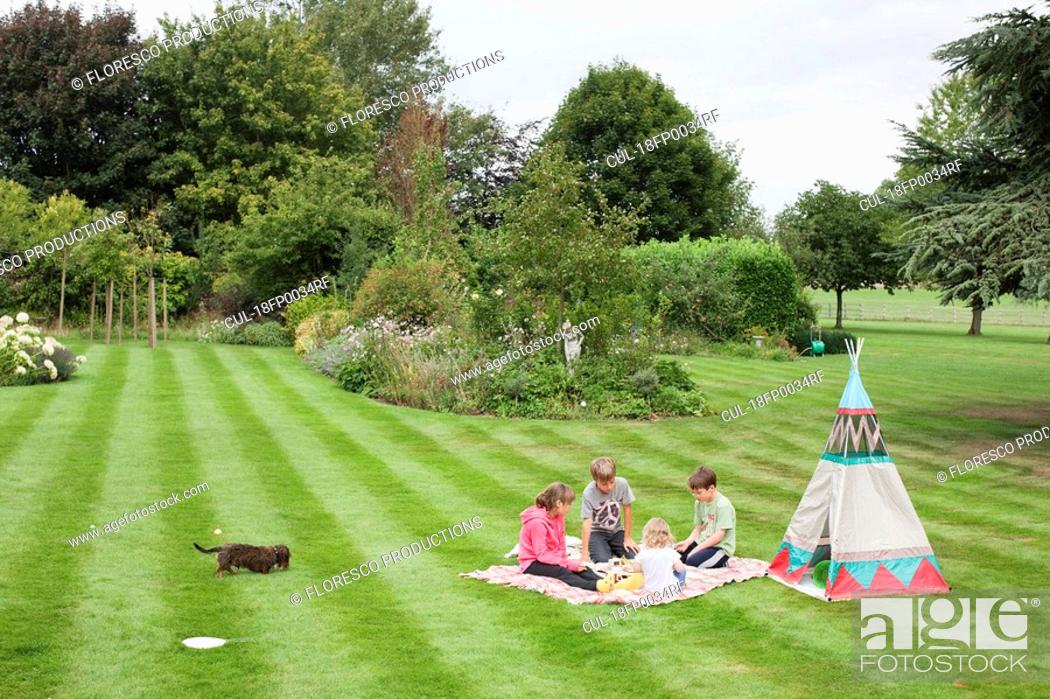 Stock Photo: Children having picnic beside teepee.