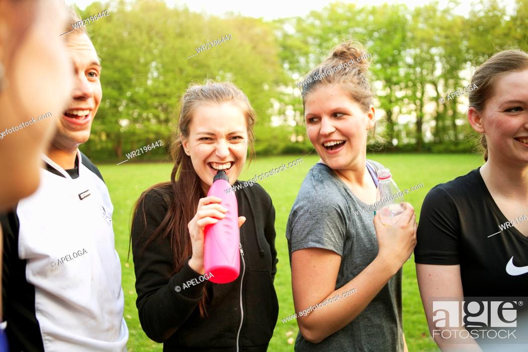 Stock Photo: Happy friends drinking water at grassy field.