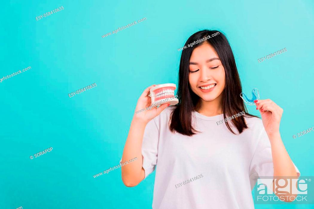 Imagen: Portrait young Asian beautiful woman smiling holding silicone orthodontic retainers for teeth retaining tools after removable braces.