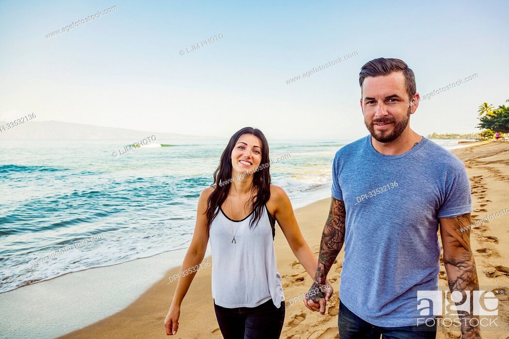 Photo de stock: Portrait of a couple walking down Ka'anapali Beach holding hands; Ka'anapali, Maui, Hawaii, United States of America.