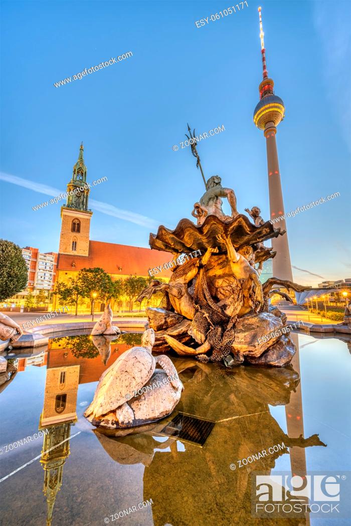 Stock Photo: Der Neptunbrunnen am Alexanderplatz in Berlin bei Sonnenaufgang mit dem berühmten Fernsehturm und der Marienkirche.
