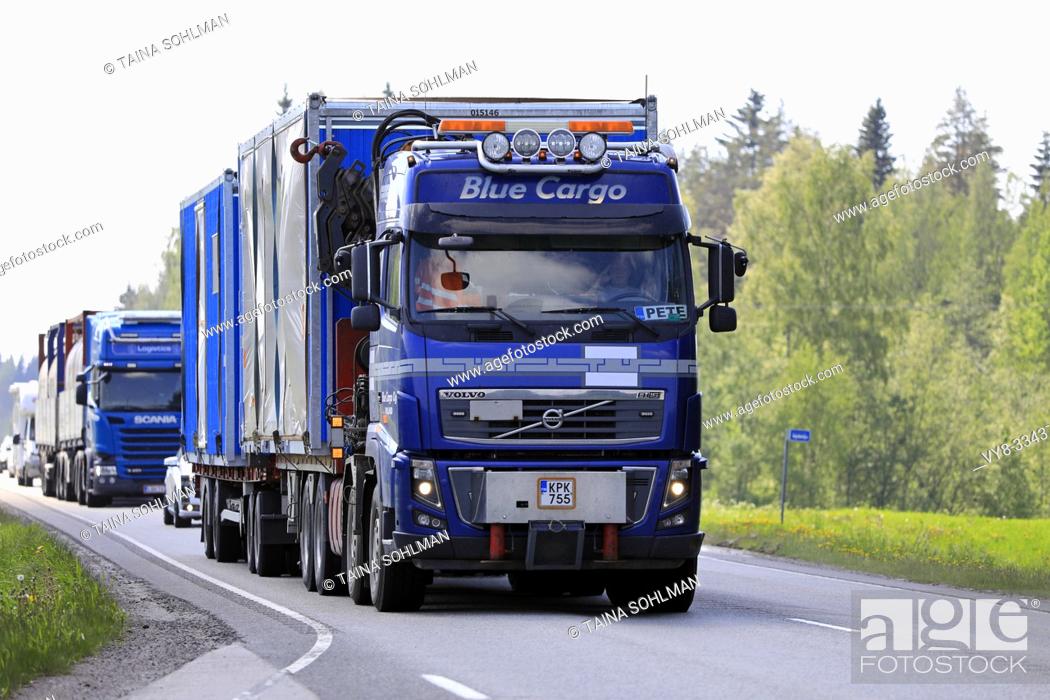 Stock Photo: Uurainen, Finland. June 7, 2019. Blue Volvo FH16 truck of Blue Cargo Oy pulls portable cabins on trailer in highway traffic with another lorry.