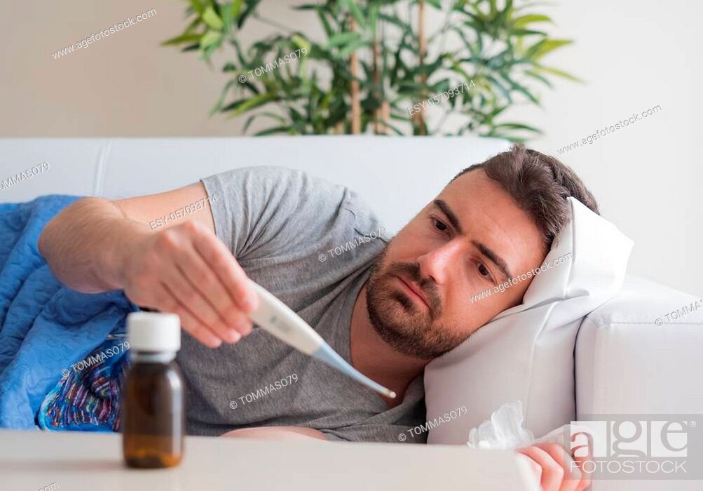 Stock Photo: Ill man portrait suffering fever checking thermometer.