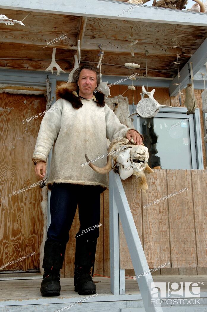 Stock Photo: Man with Musk Ox Skull on porch, Cambridge Bay, Nunavut.