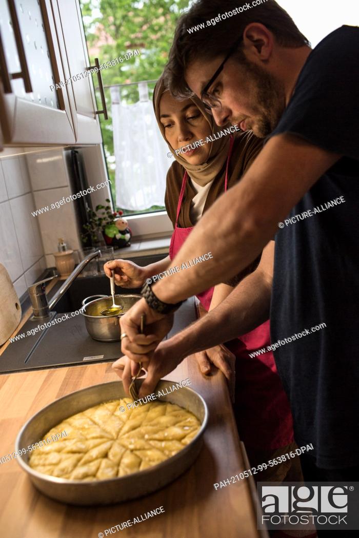 Stock Photo: PRODUCTION - 10 May 2021, North Rhine-Westphalia, Minden: Hatice Bahadir (l) and Abdurrahman Bahadir prepare baklava together in their kitchen.