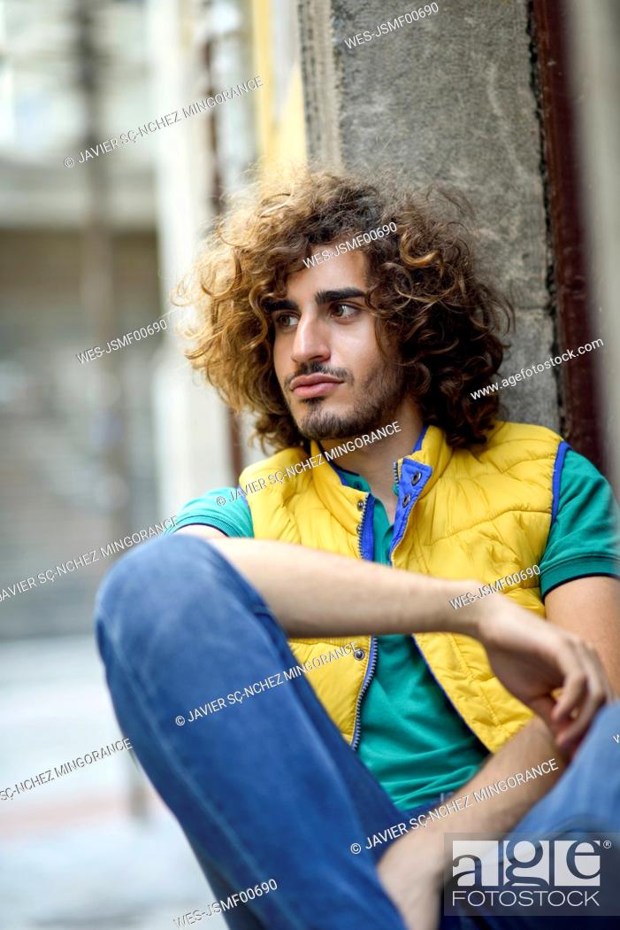 Portrait of young man with beard and curly hair wearing yellow waistcoat  watching something, Stock Photo, Picture And Royalty Free Image. Pic.  WES-JSMF00690 | agefotostock