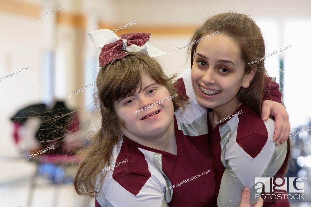 Stock Photo: Portrait of two cheerleaders hugging each other, one with Down Syndrome.