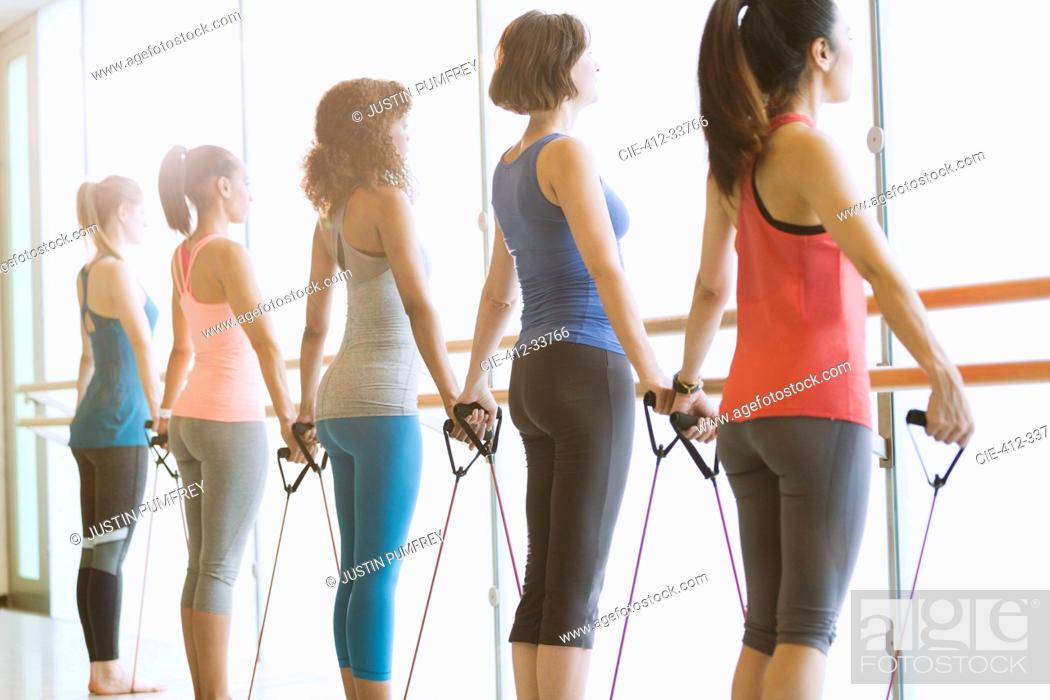 Stock Photo: Women exercising with resistance bands at barre in exercise class gym studio.