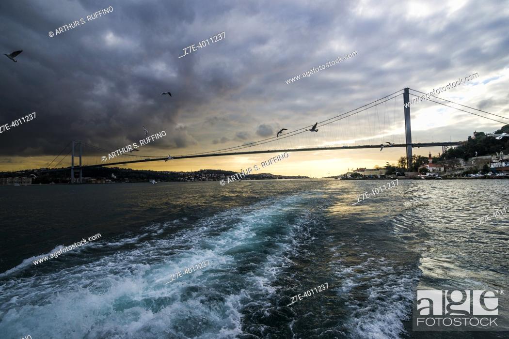 Stock Photo: Bosphorus Bridge spanning over Bosphorus Strait connecting Europe and Asia. Bosphorus Sunset Cruise on an overcast day. Istanbul, Türkiye (Republic of Türkiye).