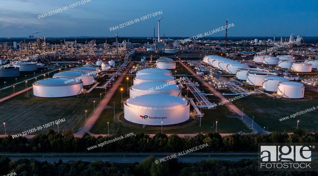 Imagen: 04 October 2022, Saxony-Anhalt, Leuna: Behind the illuminated tank farm, the facilities of the Total refinery and the chemical park rise into the air (aerial.