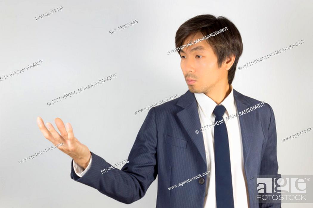 Stock Photo: Young Asian Portrait Businessman in Navy Blue Suit Show Hand and Looking Palm of Hand on Grey Background at Right Frame.